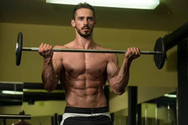 Bodybuilder utför biceps lockar med en skivstång — Stockfoto