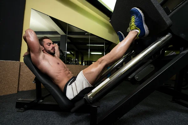 Jambes d'exercice de jeune homme sur la machine de presse — Photo