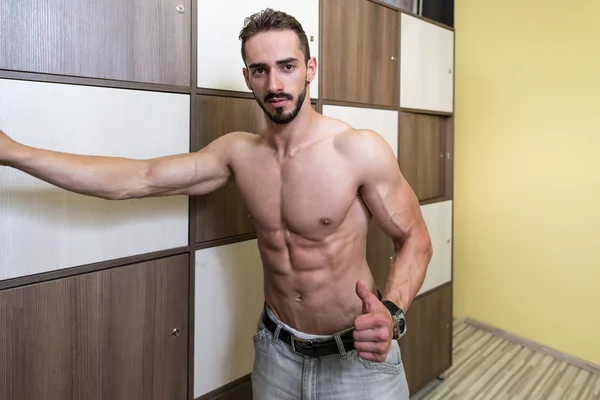 Construtor de corpo mudando de roupa na sala de armário de ginástica — Fotografia de Stock