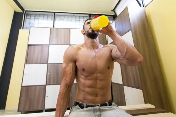 Uomo muscolare che beve acqua dallo shaker — Foto Stock