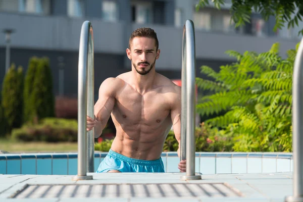 Homem descansando relaxado na borda da piscina — Fotografia de Stock