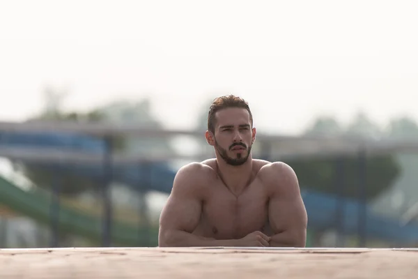 Homem descansando seus braços na borda da piscina — Fotografia de Stock