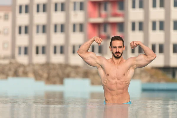 Doppelbizeps posiert im Schwimmbad — Stockfoto