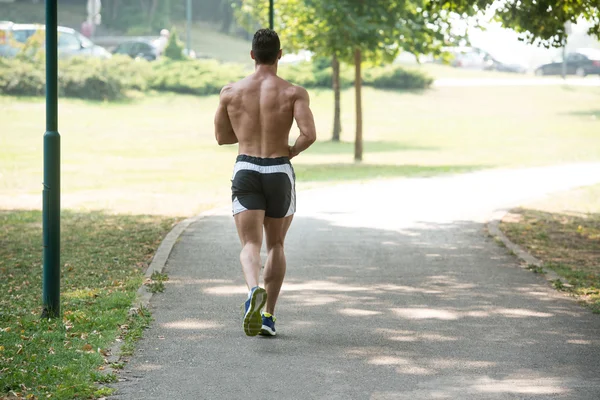 Bodybuilder Runner jogging podczas treningu na świeżym powietrzu w parku — Zdjęcie stockowe