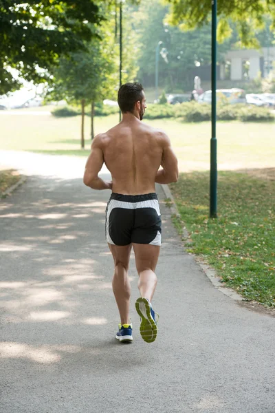 Junger schöner Mann läuft im Park — Stockfoto