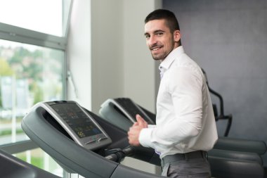 Spor salonunda koşu bandı üzerinde çalışan iş adamı
