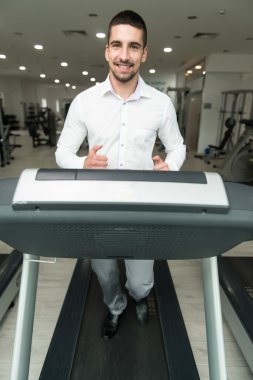 Spor salonunda koşu bandı üzerinde çalışan iş adamı