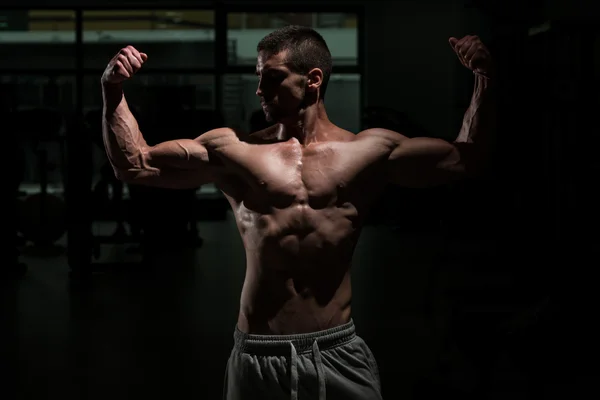 Biceps poser dans une chambre sombre — Photo