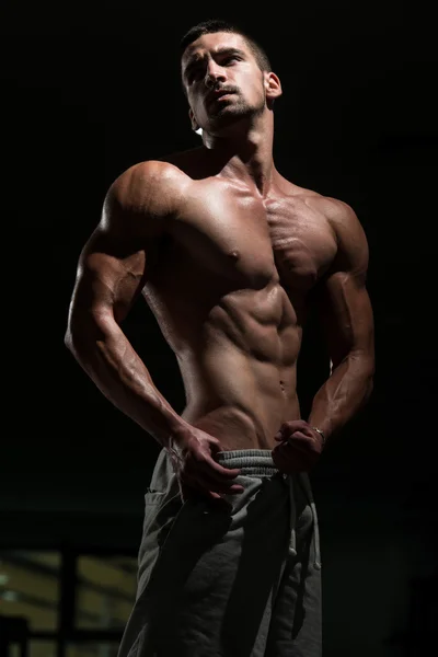 Homem fisiculturista posando no ginásio — Fotografia de Stock