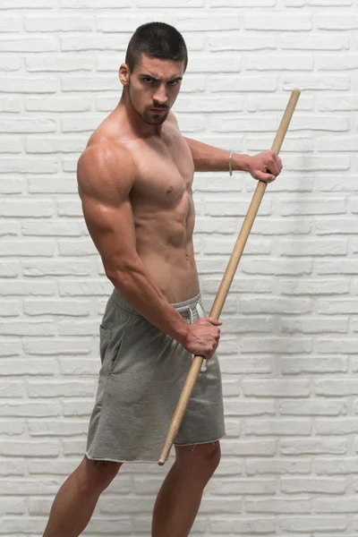Fisiculturista está se exercitando com vara na parede — Fotografia de Stock