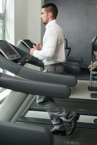 Homme d'affaires courant sur tapis roulant dans la salle de gym — Photo