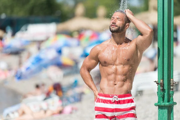 Bonito muscular homem leva um chuveiro ao ar livre — Fotografia de Stock