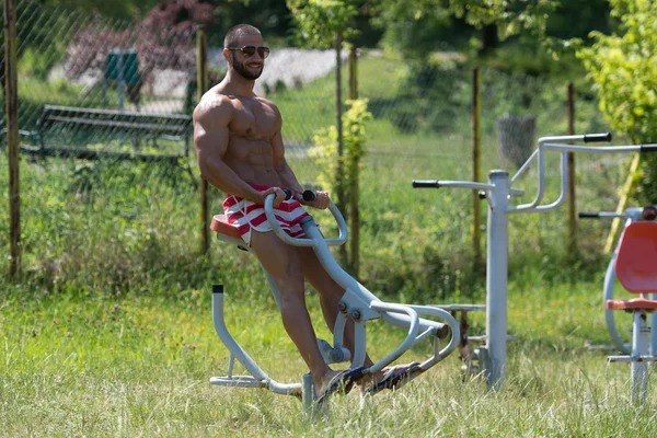 Тренировка мускулистого человека на детской площадке в парке — стоковое фото