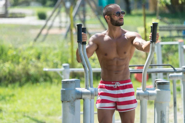 Allenamento muscolare uomo sul campo da giuoco nel parco — Foto Stock