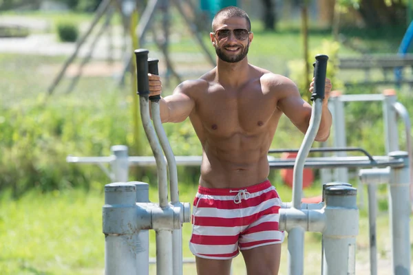 Homem muscular treinando no parque infantil no parque — Fotografia de Stock