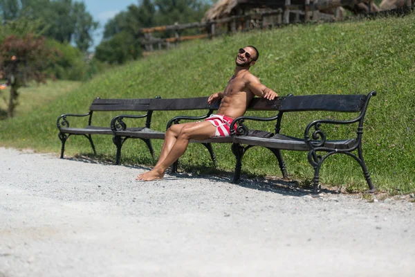 Sorridente bel ragazzo che riposa sulla panchina all'aperto — Foto Stock