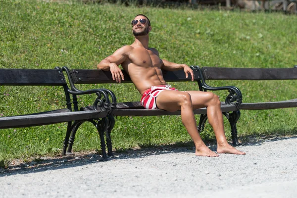 屋外のベンチで休んでハンサムな男の笑みを浮かべてください。 — ストック写真