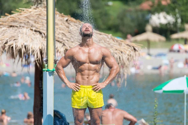 Bel homme musculaire prend une douche en plein air — Photo