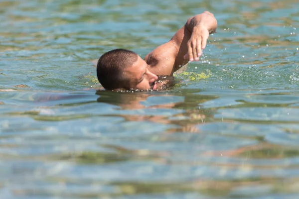 Homem jovem nadando em água verde — Fotografia de Stock