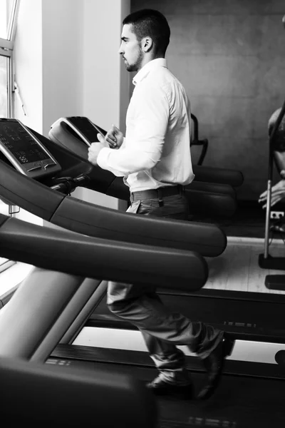 Homme d'affaires courant sur tapis roulant dans la salle de gym — Photo