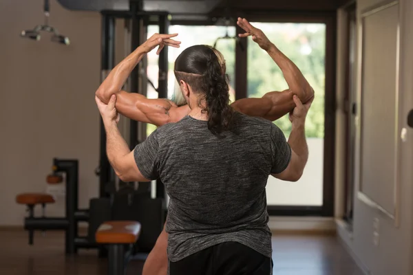 Vrouw poseren Bodybuilding Poses en Partner corrigeren haar — Stockfoto