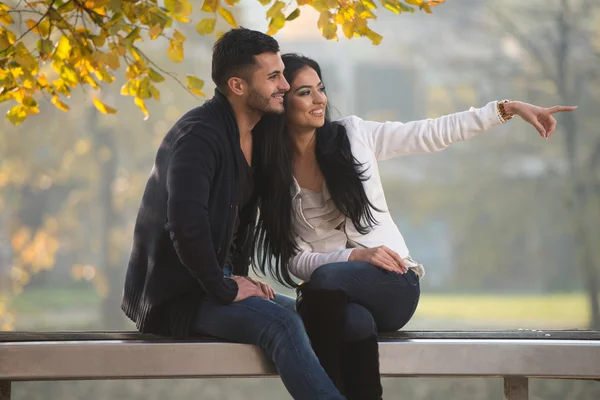 Mujer joven mostrando algo al hombre durante el otoño — Foto de Stock