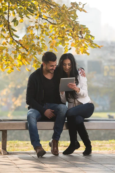 Hombre y mujer mira la tableta electrónica en el parque —  Fotos de Stock