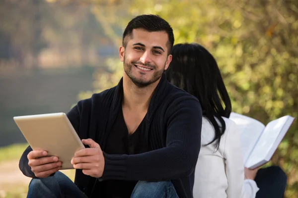 Par njuter Digtial Tablet och bok — Stockfoto