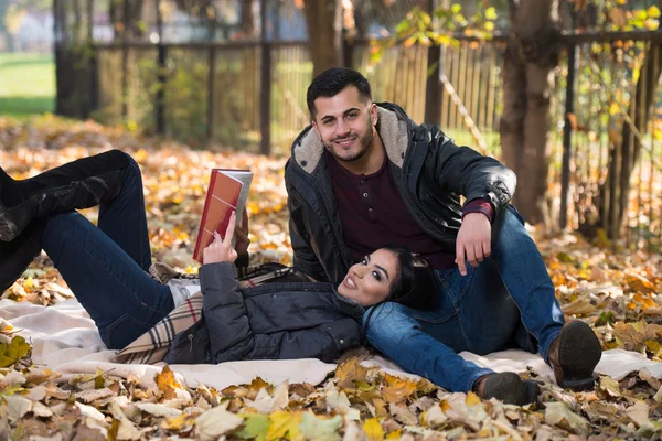 Coppia Godersi la lettura del libro nel parco d'autunno — Foto Stock