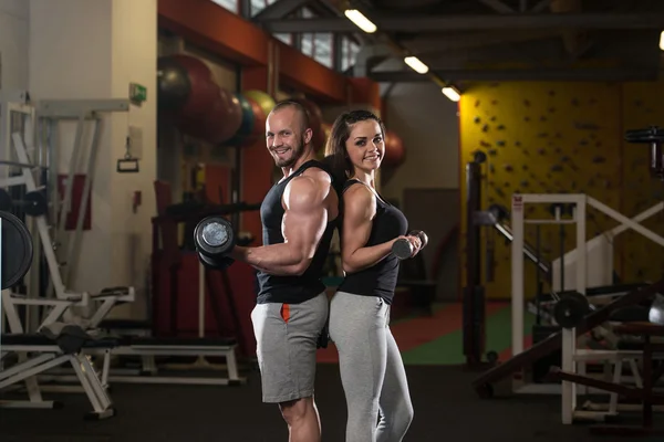 Jovem casal fazendo exercício para bíceps com halteres — Fotografia de Stock