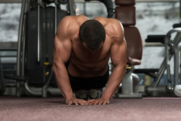 Joven haciendo prensa sube en el gimnasio — Foto de Stock