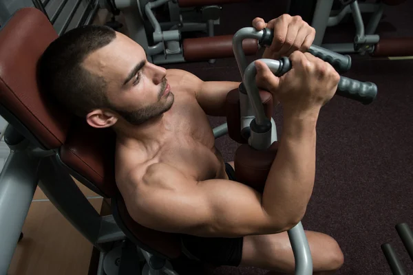 Muskulös man på en fjäril maskin i gymmet — Stockfoto