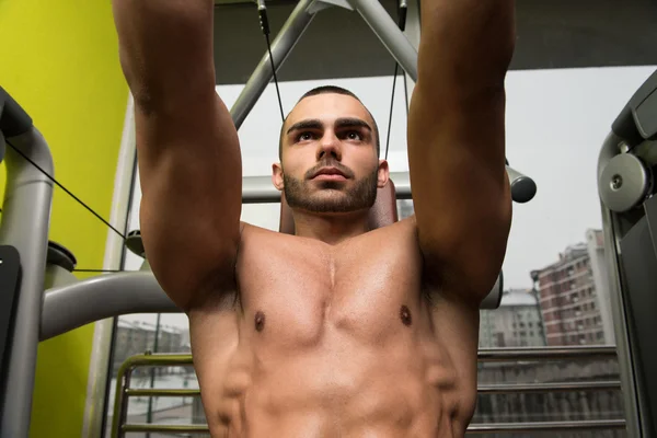 Musclé mâle sur une machine papillon dans la salle de gym — Photo