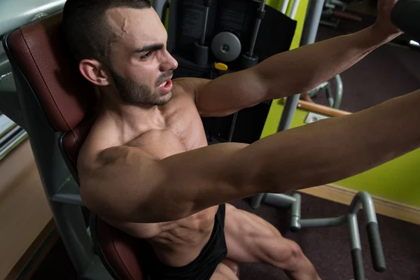 Masculino muscular en una máquina de mariposa en el gimnasio —  Fotos de Stock