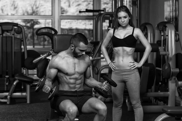 Pareja joven haciendo ejercicio para bíceps con cascabeles —  Fotos de Stock