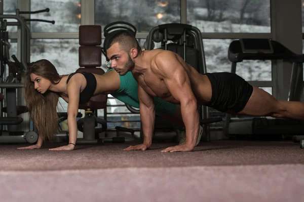 Νεαρό ζευγάρι να κάνει Pushups στο γυμναστήριο — Φωτογραφία Αρχείου
