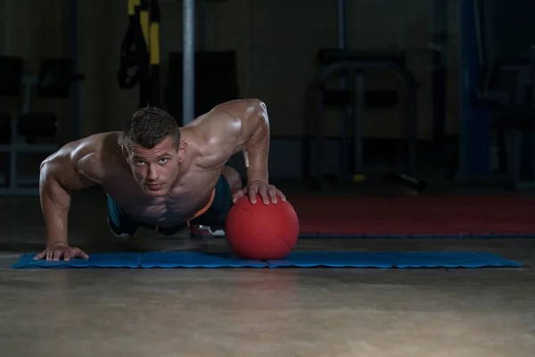 Hombre joven haciendo ejercicio Push Ups en bola de la medicina — Foto de Stock