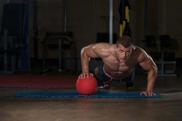 Ung Man gör Press Ups på medicin boll — Stockfoto