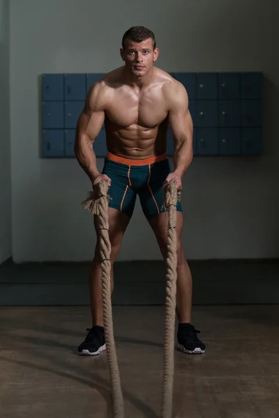 Młody mężczyzna walczy liny w siłowni treningu ćwiczenie — Zdjęcie stockowe