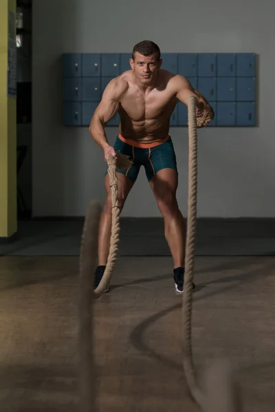 Junger Mann kämpft bei Fitnesstraining mit Seilen — Stockfoto