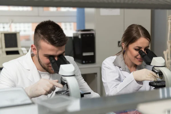 Un par de científicos mirando dentro de un microscopio —  Fotos de Stock