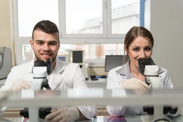 Un par de científicos mirando dentro de un microscopio —  Fotos de Stock