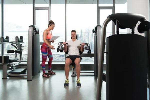 Personal trainer ajudando cliente no ginásio — Fotografia de Stock