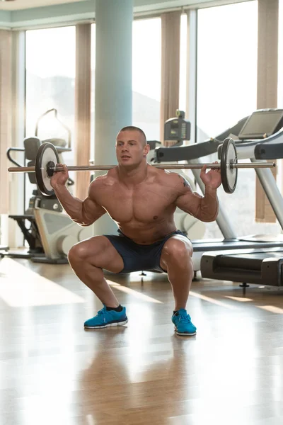 Mladý muž dělá squaty barbell — Stock fotografie