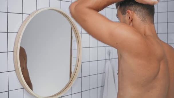 Człowiek Bez Koszulki Spryskując Dezodorantem Patrząc Lustro Łazience — Wideo stockowe