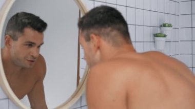 Banyodaki aynaya bakan bir adam. 