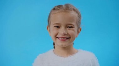 Mavi, pofuduk kazaklı, gülümseyen kız.