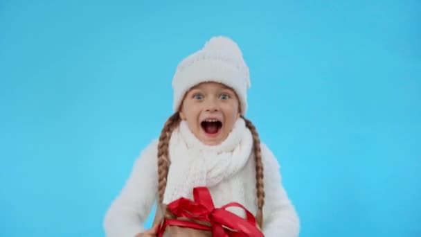 穿针织白色冬装 头戴蓝色礼品盒的快乐女孩 — 图库视频影像