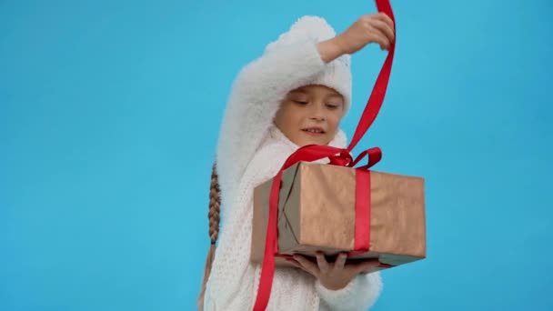 穿针织白色冬装的女孩打开礼品盒 蓝色隔离 — 图库视频影像