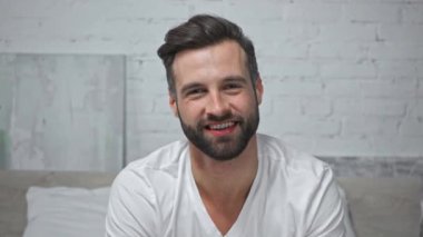 Mutlu adam kameraya bakarken konuşuyor ve gülüyor.